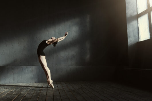Flexible,Ballet,Dancer,Stretching,In,The,Dark,Lighted,Studio
